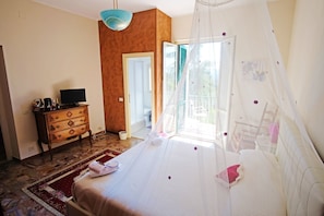 Un dormitorio con cama, cómoda, televisor y ventana con vistas al exterior.