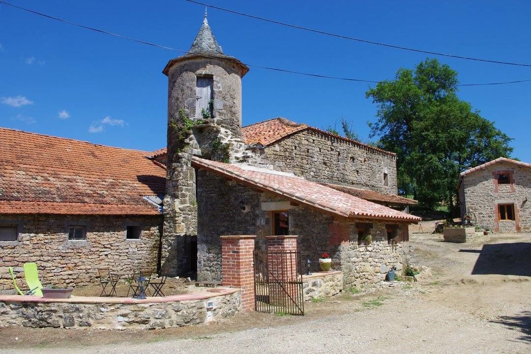 Un edificio de piedra con una torre, techo de tejas rojas y una pequeña entrada.