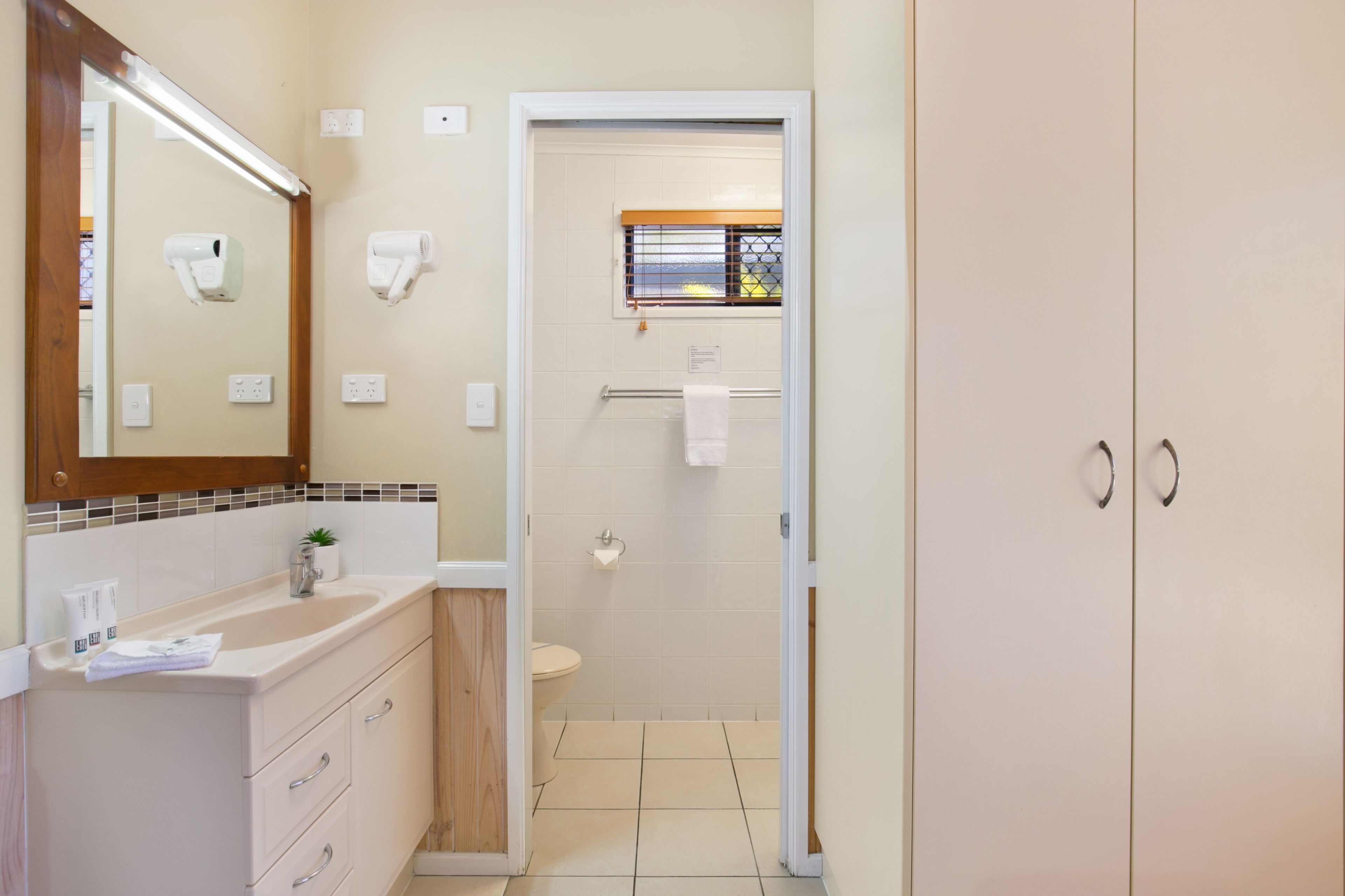 A bathroom with a sink, mirror, towel rack, and a shower area.