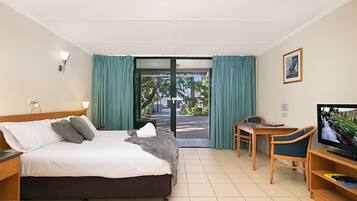 A hotel room with a bed, a desk, a chair, a television, and a view of the outside.