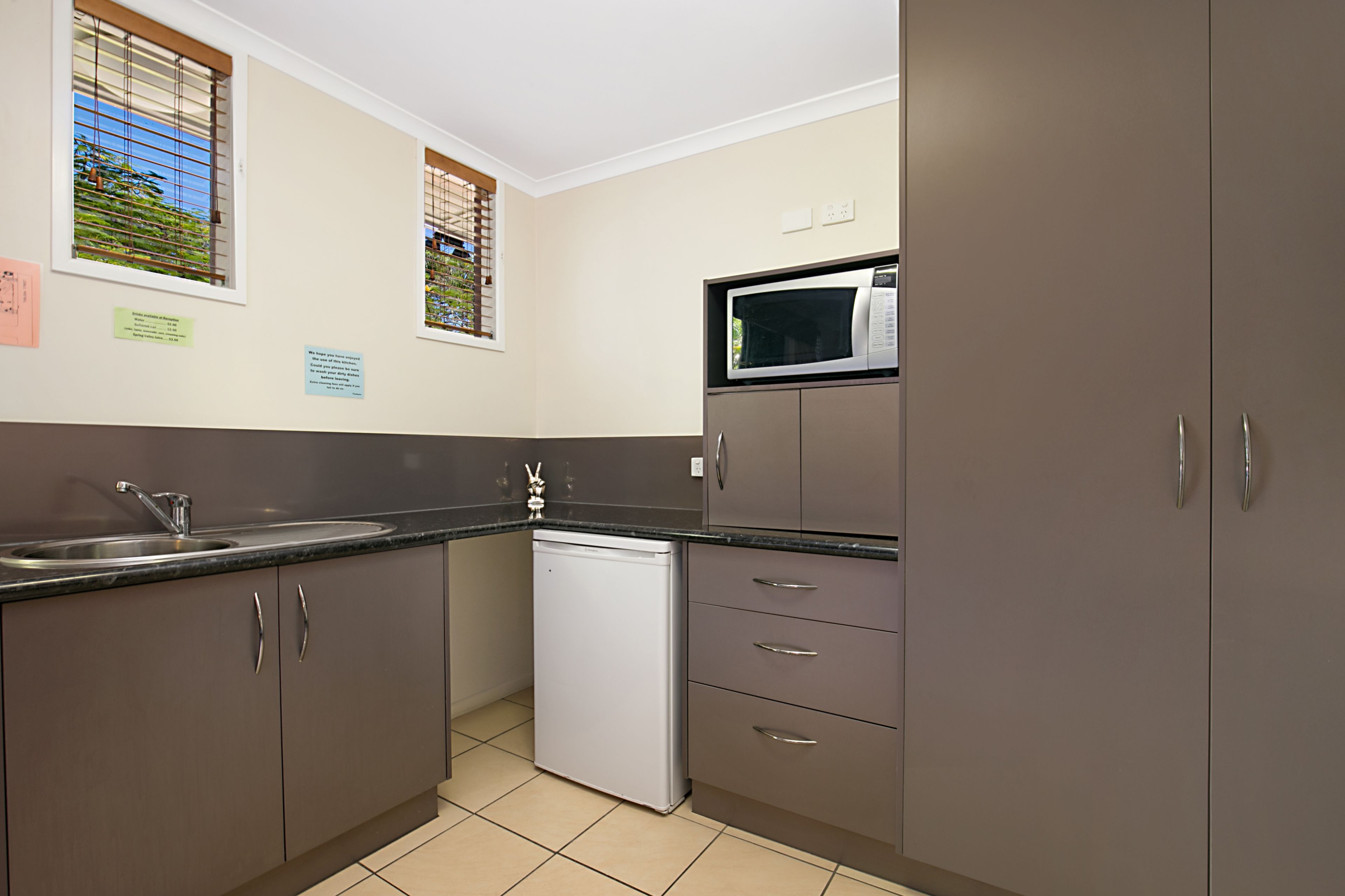 A compact kitchen with a dishwasher, a microwave, and a sink.