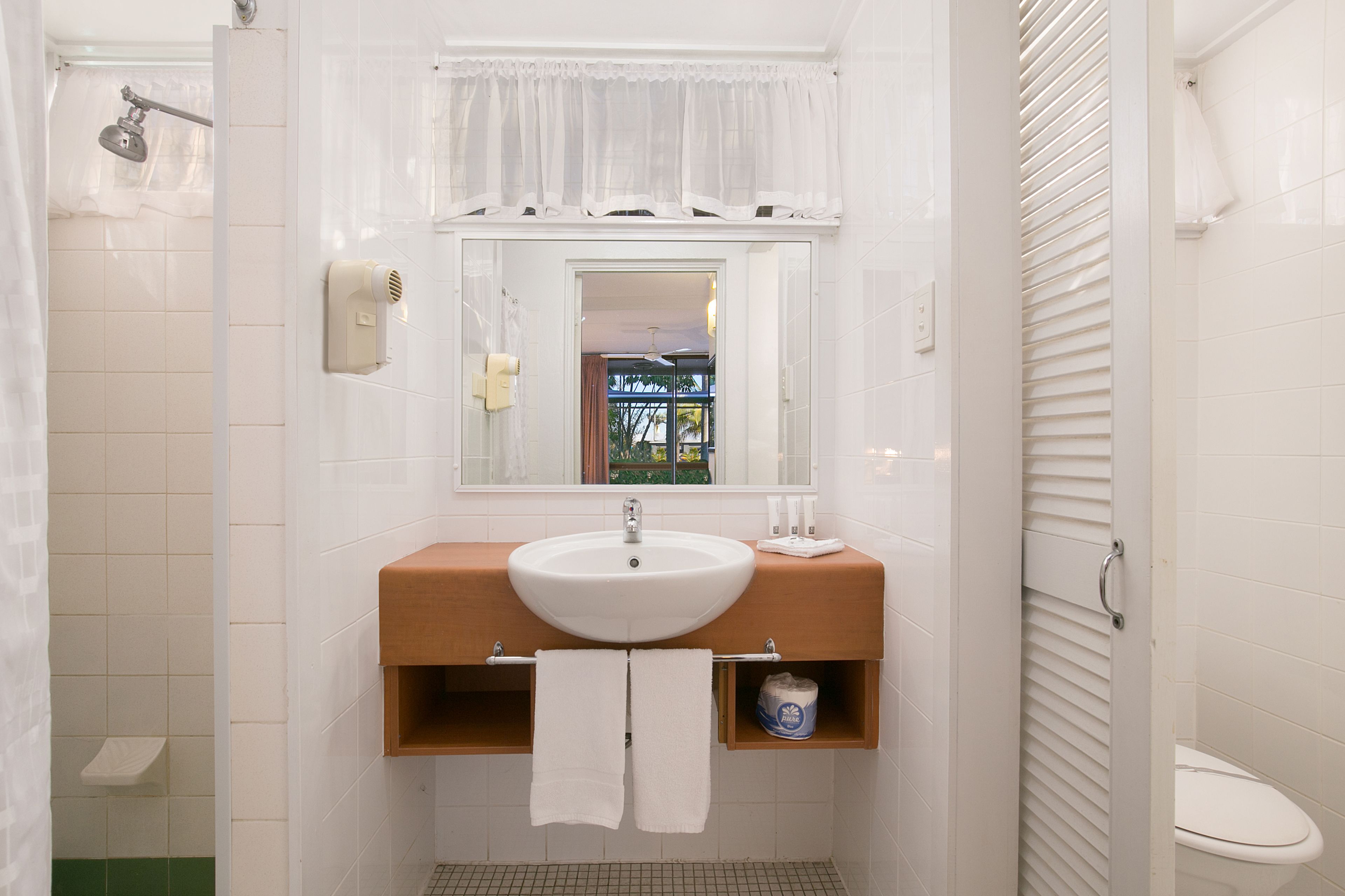 Un baño con un lavamanos blanco, un espejo y un inodoro.