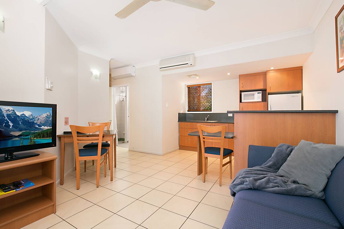 A modern living room with a television, a sofa, and a dining area with chairs and a table.