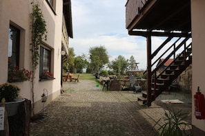 A courtyard with cobblestone flooring, a wooden staircase, and outdoor furniture. - Ferienwohnung Brunow (Neundorf)