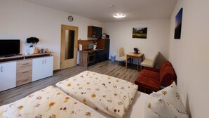 A compact room with a bed, a small kitchenette, a TV, and a dining area. - Ferienwohnung Brunow (Neundorf)