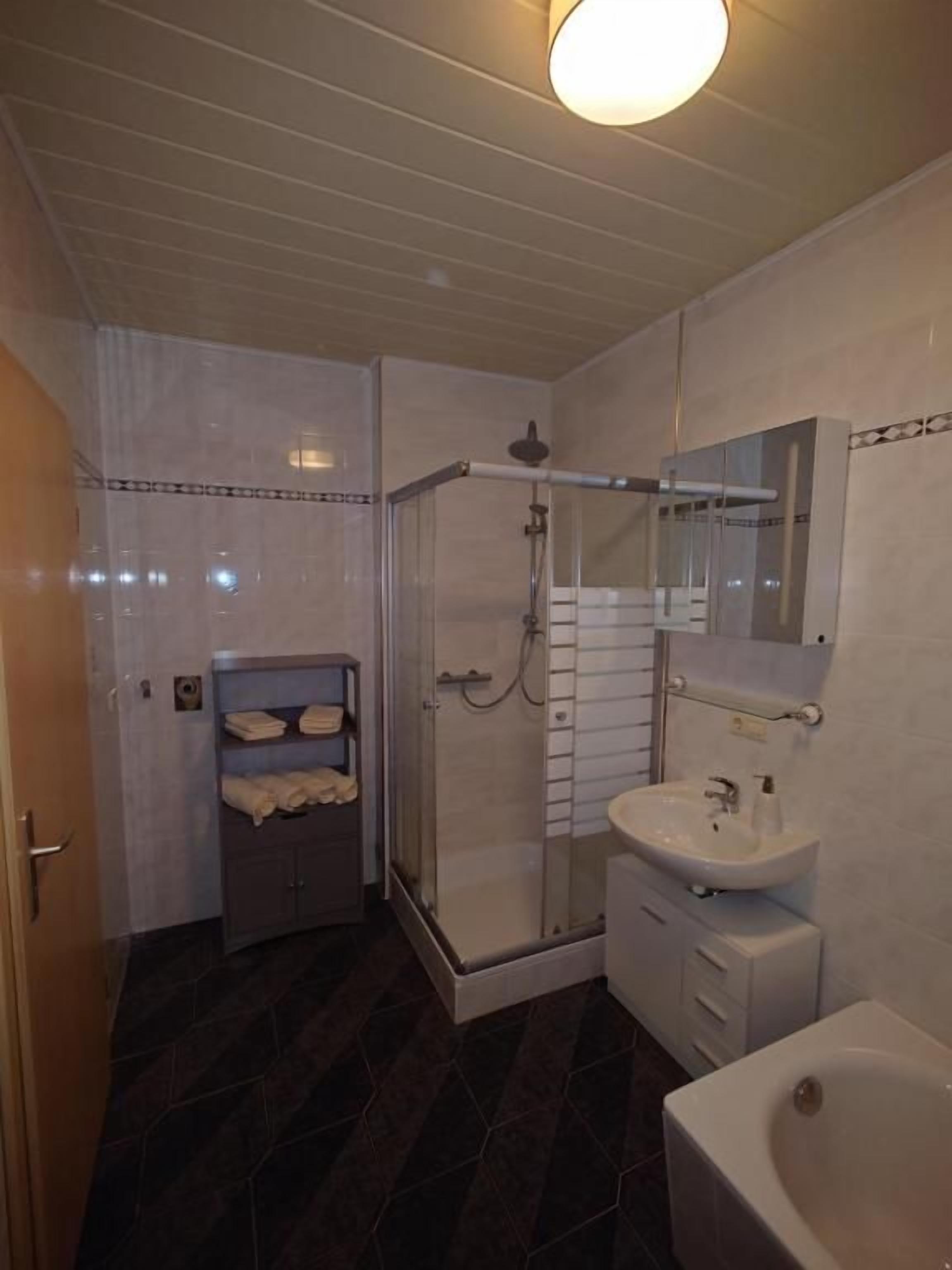 Une salle de bain avec une douche à parois de verre, un lavabo, un miroir et une baignoire.