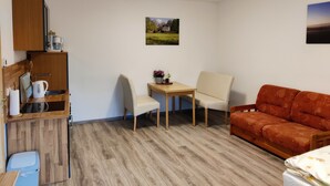 A compact living space with a kitchenette, a dining area, and a sofa. - Ferienwohnung Brunow (Neundorf)