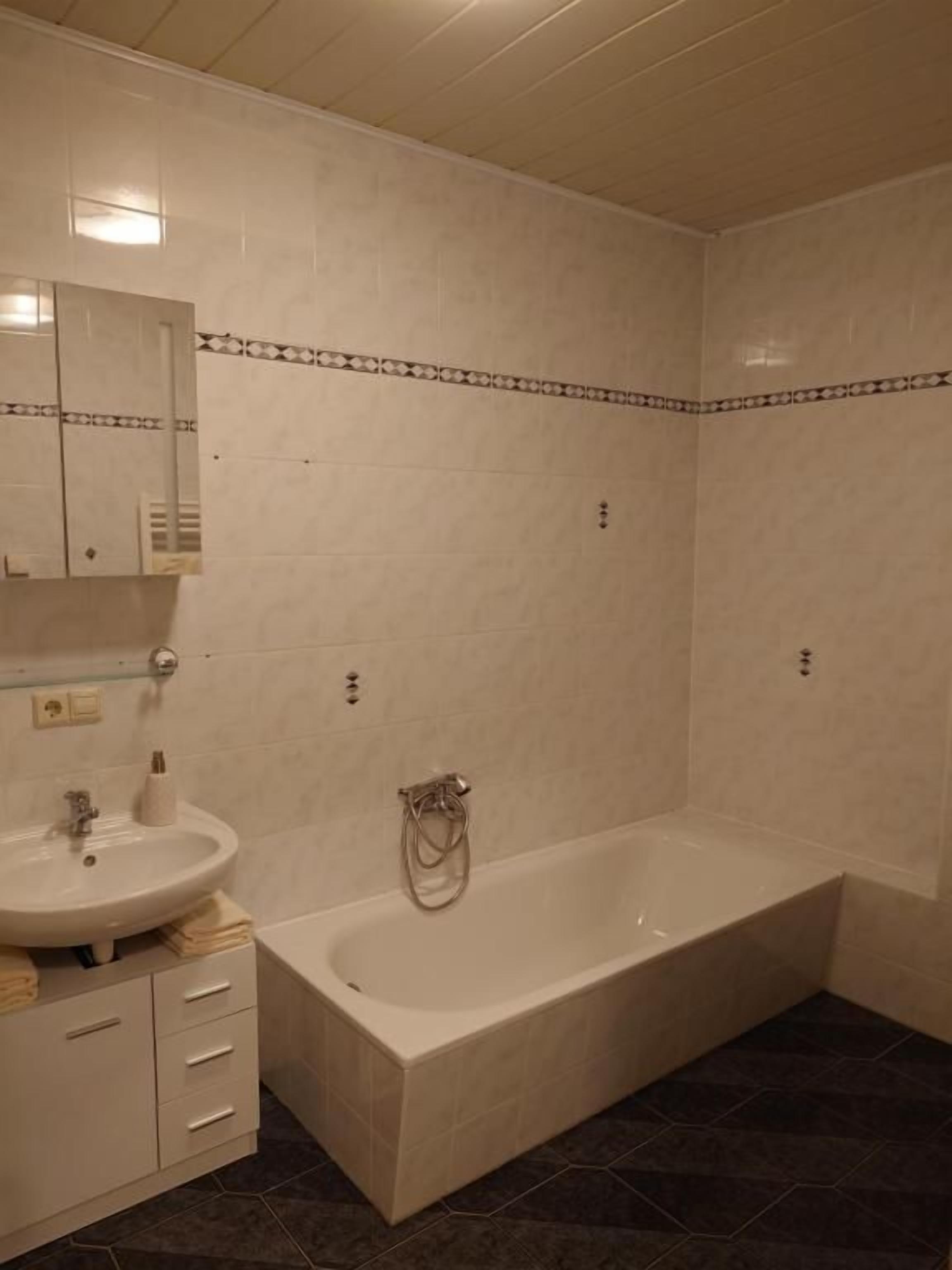 Un baño con bañera, lavamanos y espejo.