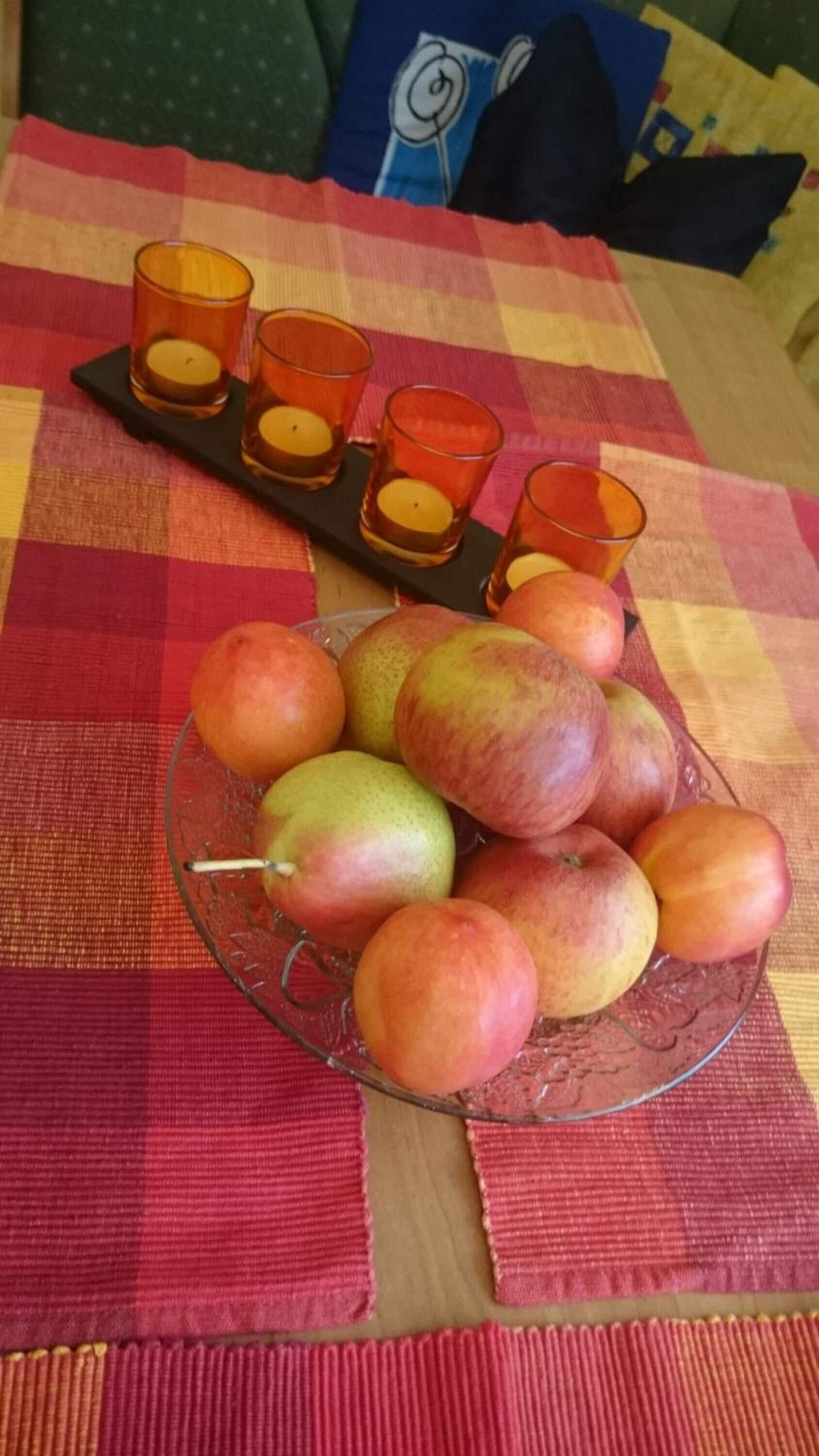 A table with a glass bowl of apples and a tray with candles.