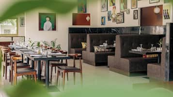 Un ristorante con un lungo tavolo, diverse cabine e varie opere d'arte appese alle pareti.