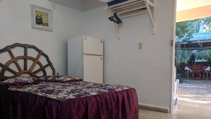 A bedroom with a bed, a white refrigerator, a wooden headboard, a wall-mounted air conditioner, and a small rug. - Casa Mirian (Candelaria)