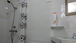 A bathroom with a shower, toilet, and a shelf with toiletries. - Casa Mirian (Candelaria)