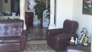 A spacious living room with a large window, a fireplace, and a staircase leading to an upper floor. - Casa Colonial Center (Cienfuegos)