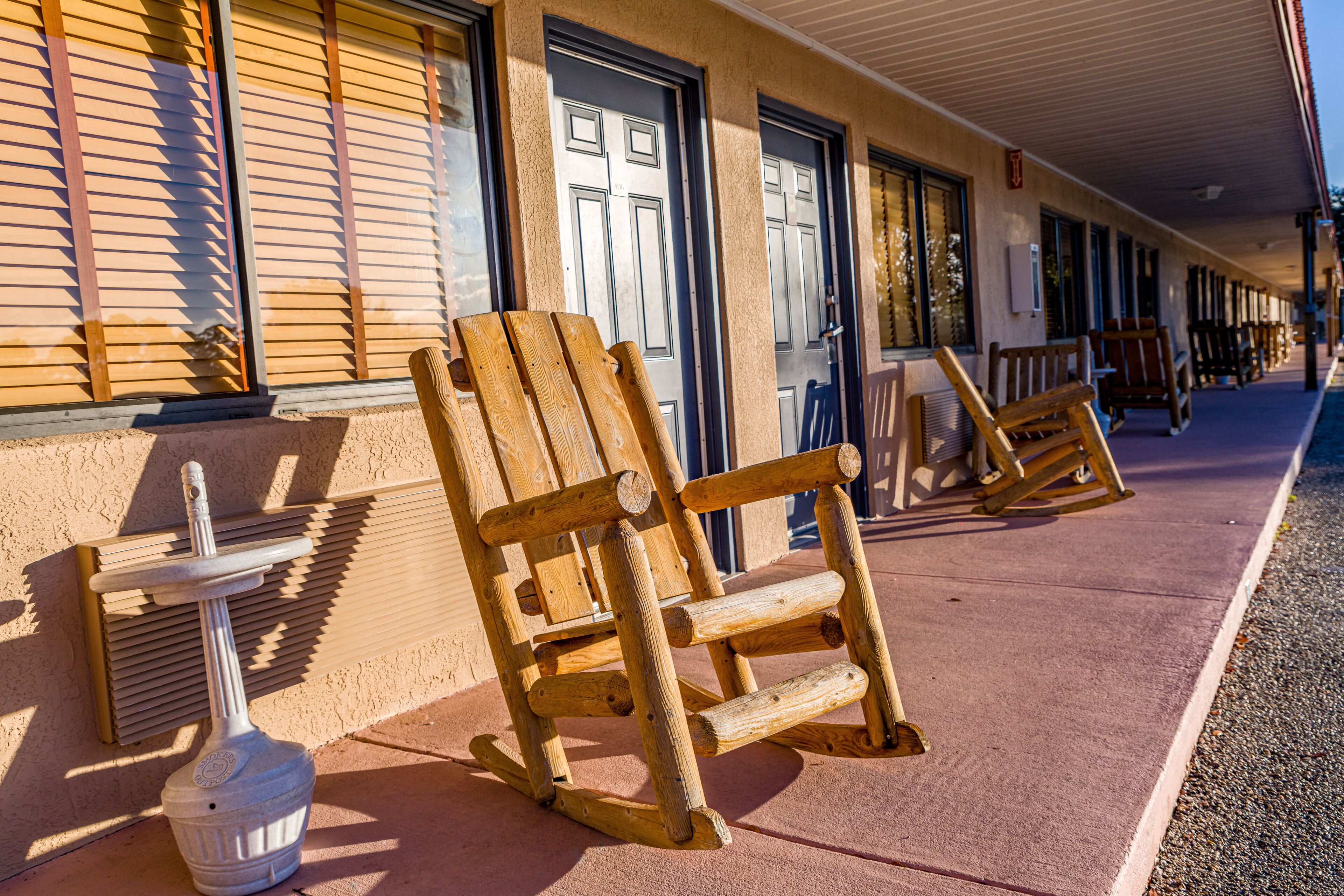 A wooden rocking chair and a small table outside a building with a porch.