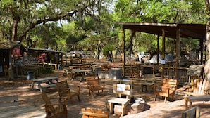 An outdoor seating area with wooden tables and chairs, a covered pavilion, and a small kiosk. - Camp Mack Lodge, Marina & RV Resort (Lake Wales)