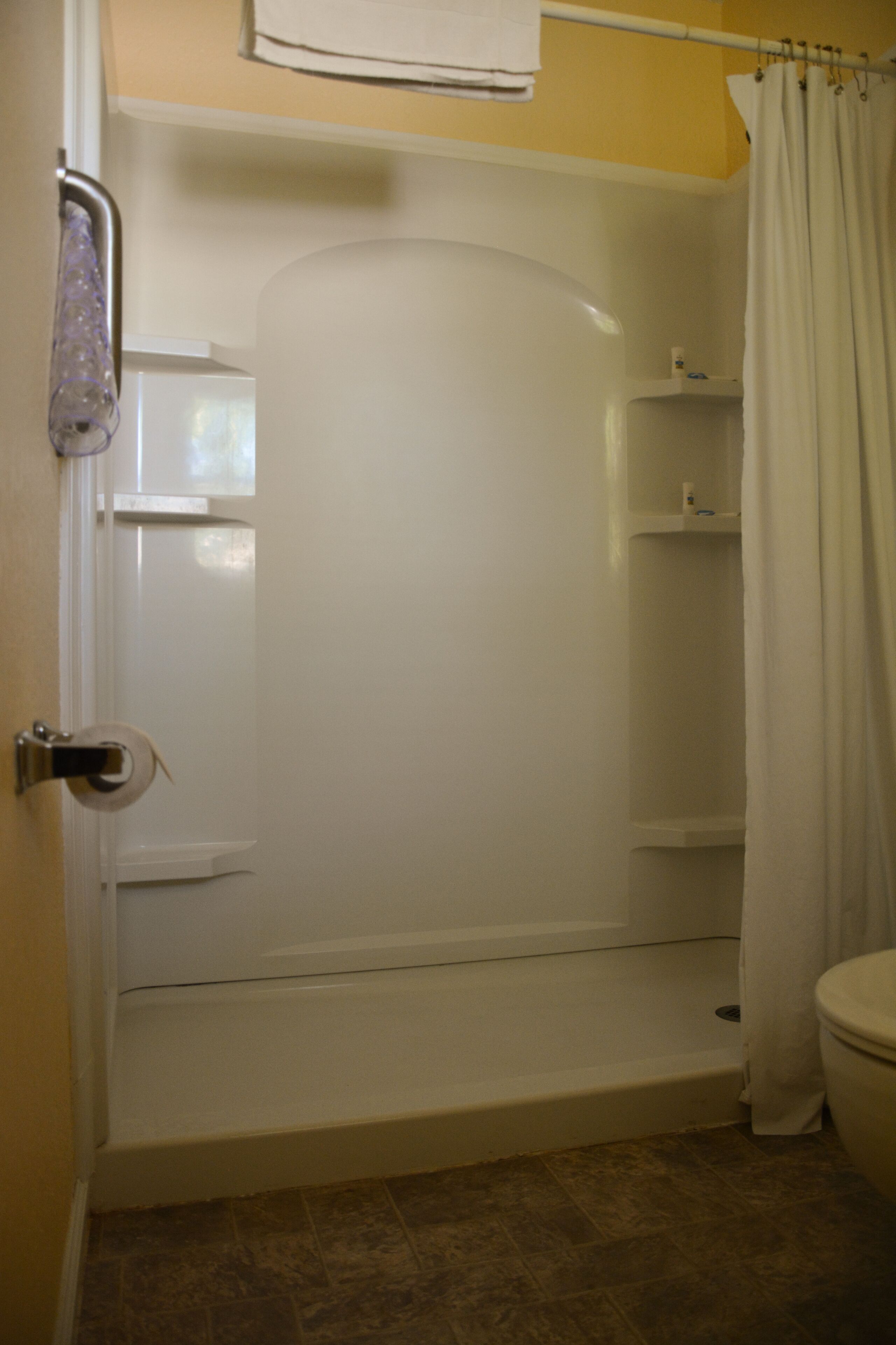 A bathroom with a shower, toilet, and a towel rack.
