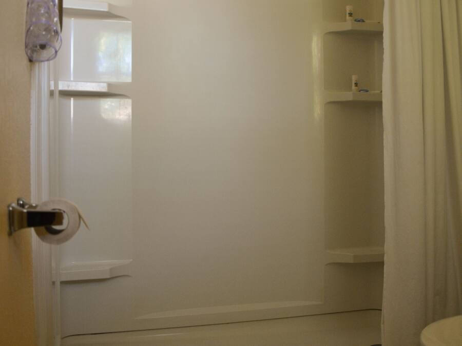 A bathroom with a shower, toilet, and a towel rack.