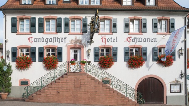A traditional European hotel with a central entrance, multiple windows with shutters, and flower boxes. - Flair Hotel Schwanen (Bad Bellingen)