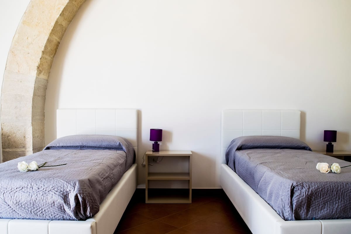 Ein Zimmer mit zwei Betten, jeweils mit Kopfteil und Nachttisch.