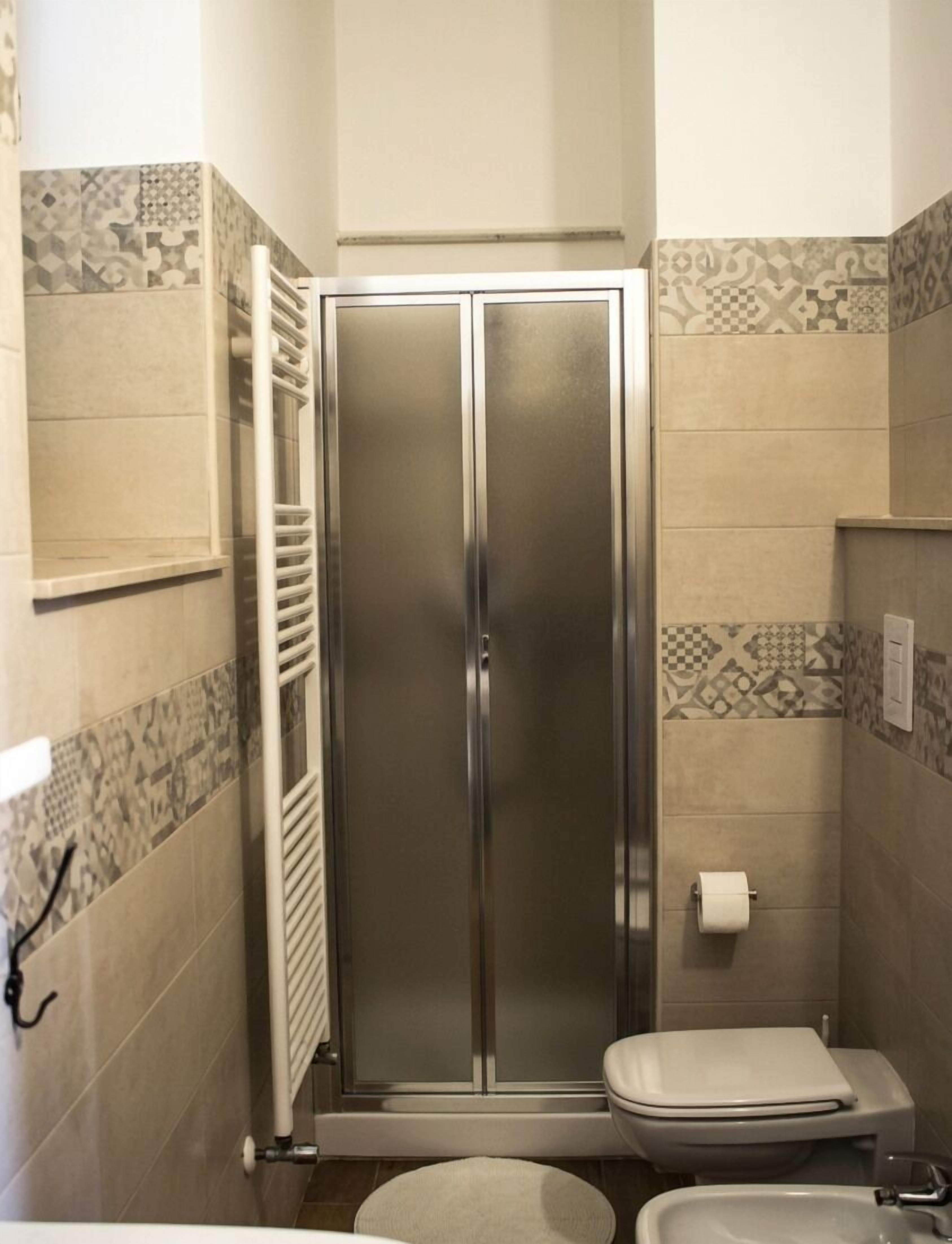 A bathroom with a shower enclosure, toilet, and sink.