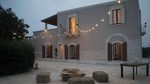 A building with a balcony, string lights, and hay bales. - Tenuta Vigna Del Noce (Corato)