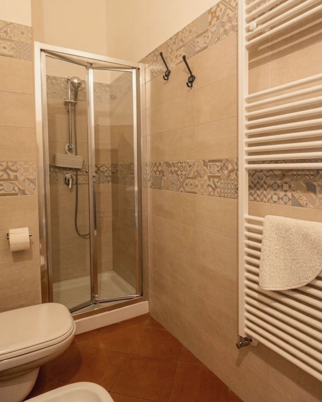 A bathroom with a glass-enclosed shower, a toilet, and a towel rack with a towel.