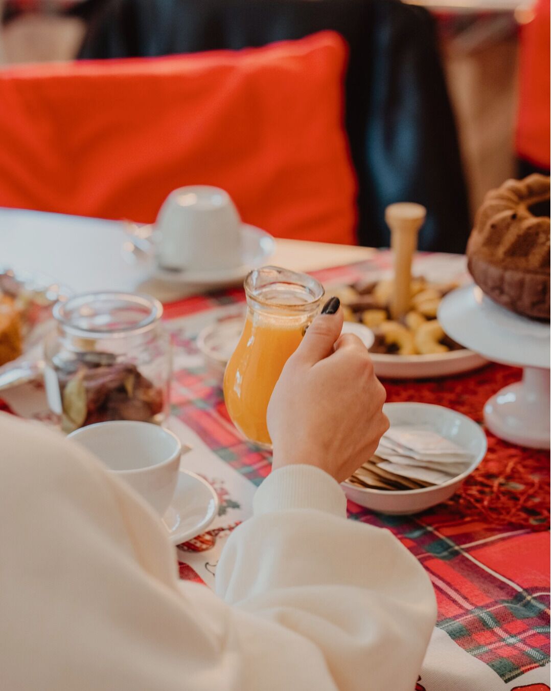 A dining table with a glass of orange juice, a white cup, and various food items.