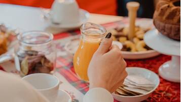 A dining table with a glass of orange juice, a white cup, and various food items.