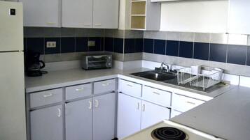 A compact kitchen with white cabinets, a built-in toaster, and a sink.