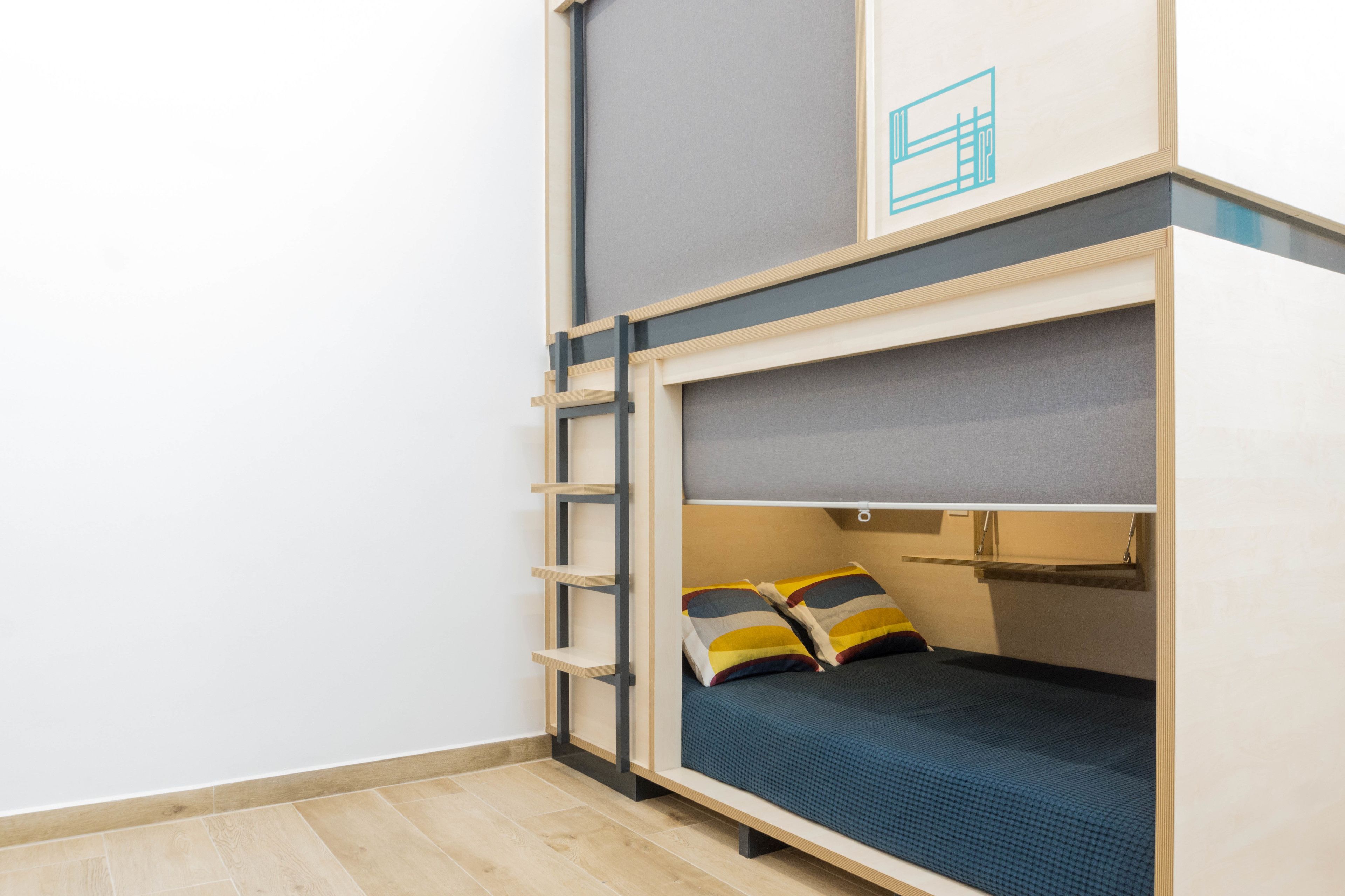 A bunk bed with a ladder, a small shelf, and a headboard with a light switch.