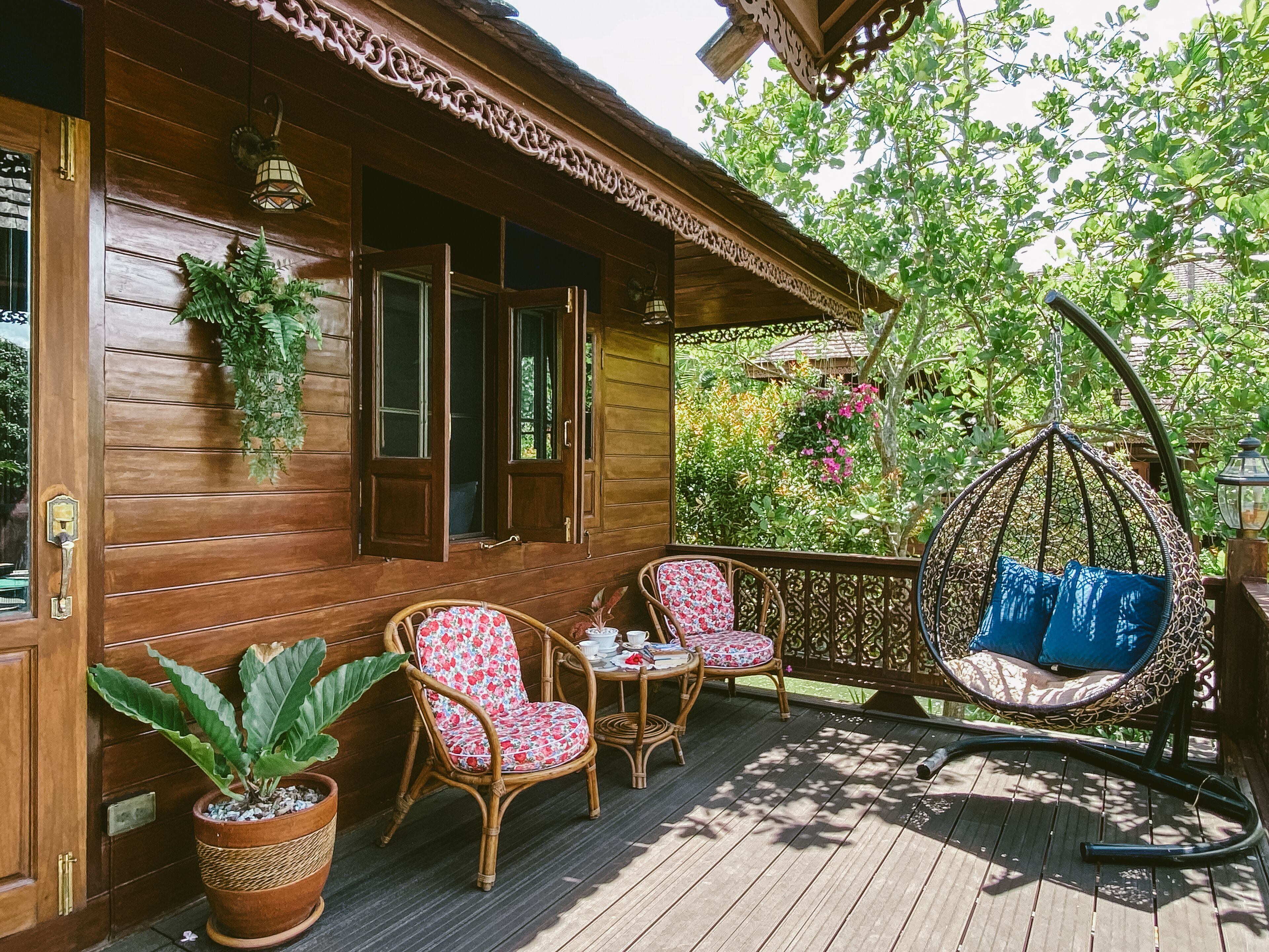 A wooden porch with wicker chairs and a hanging swing.