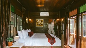 Una habitación de madera con una cama grande, una planta en maceta y una silla de mimbre.