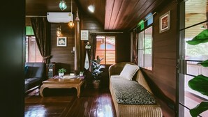 Una habitación acogedora con piso de madera, un sofá, una mesa con plantas y una ventana con cortinas.