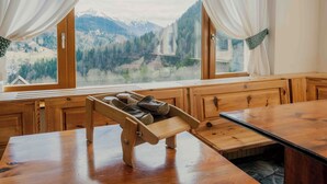 A wooden bench with a shoe rack, wooden cabinets, and a view of mountains through large windows. -  Miravalle Supersport Hotel (Forni Avoltri)