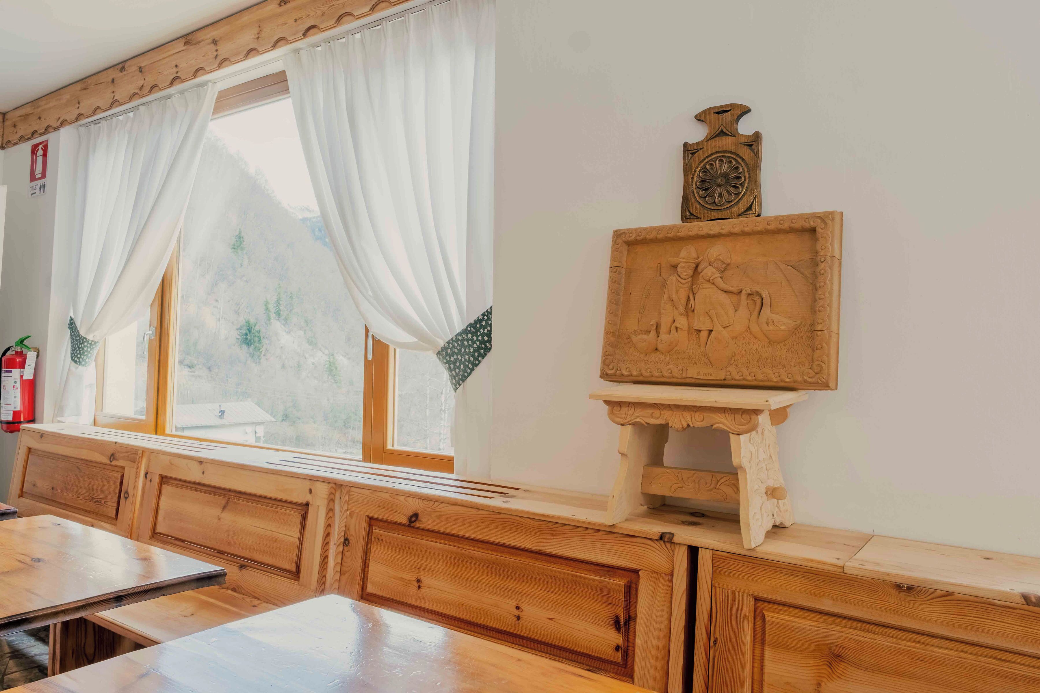 Un banc en bois avec une fenêtre, une horloge en bois et une sculpture en bois accrochée au mur.