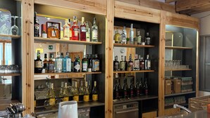 A bar area with wooden shelves stocked with various liquor bottles and glasses. -  Miravalle Supersport Hotel (Forni Avoltri)