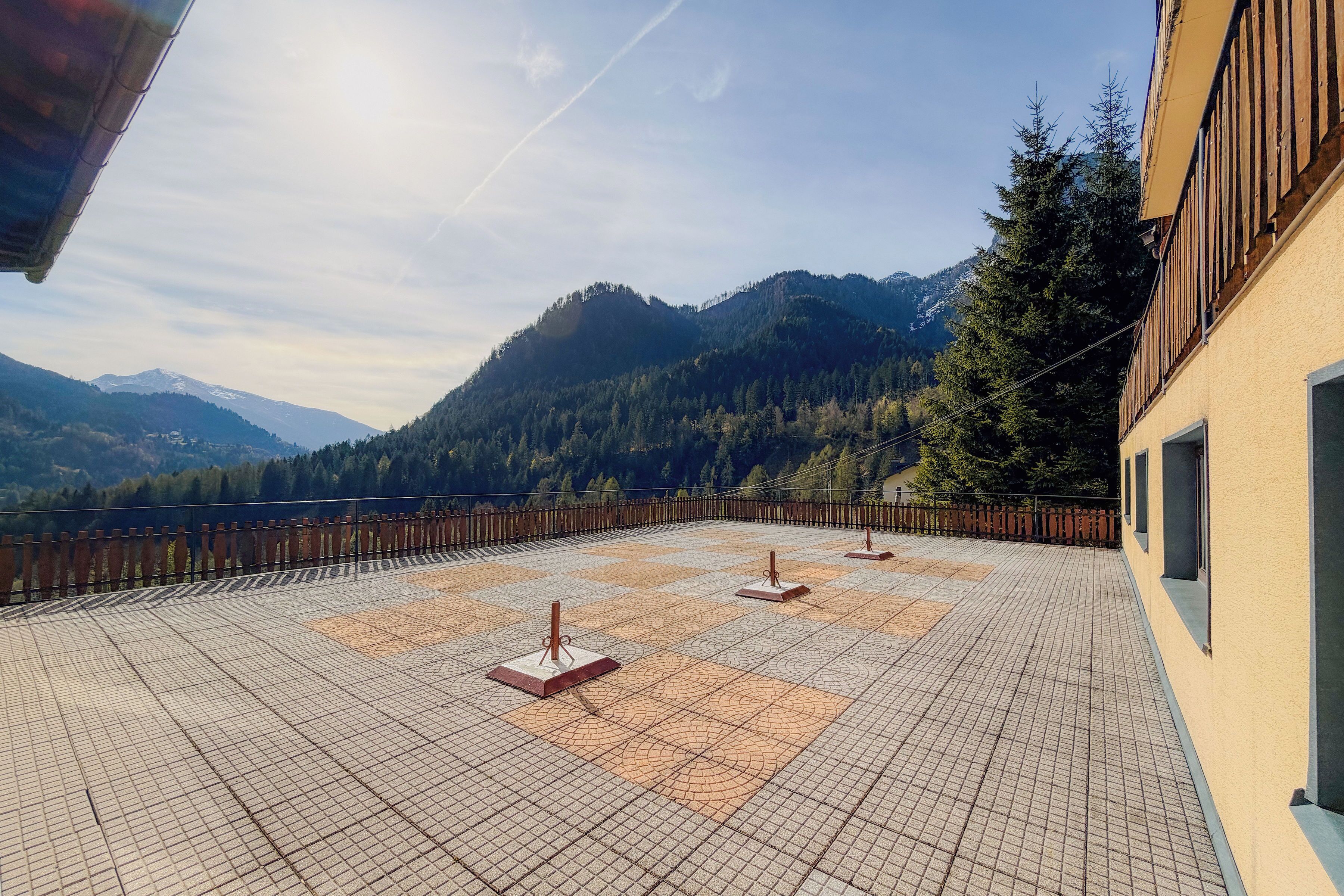 A rooftop terrace with a tiled floor, a wooden fence, and a view of mountains.