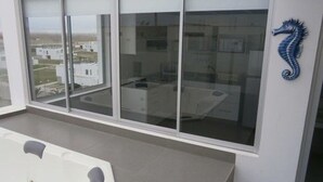 A modern room with large windows, a blue seahorse decoration, and a view of buildings outside.