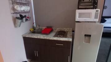 A compact kitchenette with a microwave, sink, and storage cabinets.