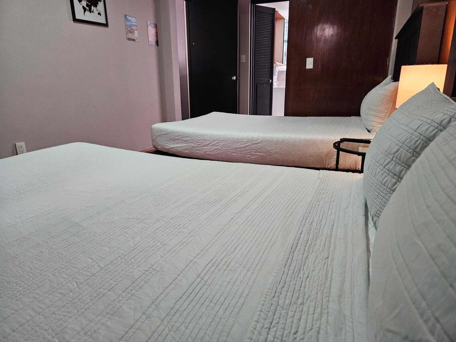 A room with two beds, a wooden door, and a small table.