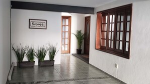 A hallway with tiled flooring, a potted plant, a framed welcome sign, and a wooden door. - Hotel Singular Coyoacán (Mexico City)
