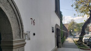 A white building with the number 76 on its facade, a small door, and a mailbox. - Hotel Singular Coyoacán (Mexico City)