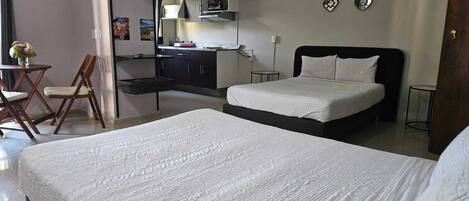 Habitación de hotel con una cama grande, un escritorio con una silla, kitchenette y un baño.
