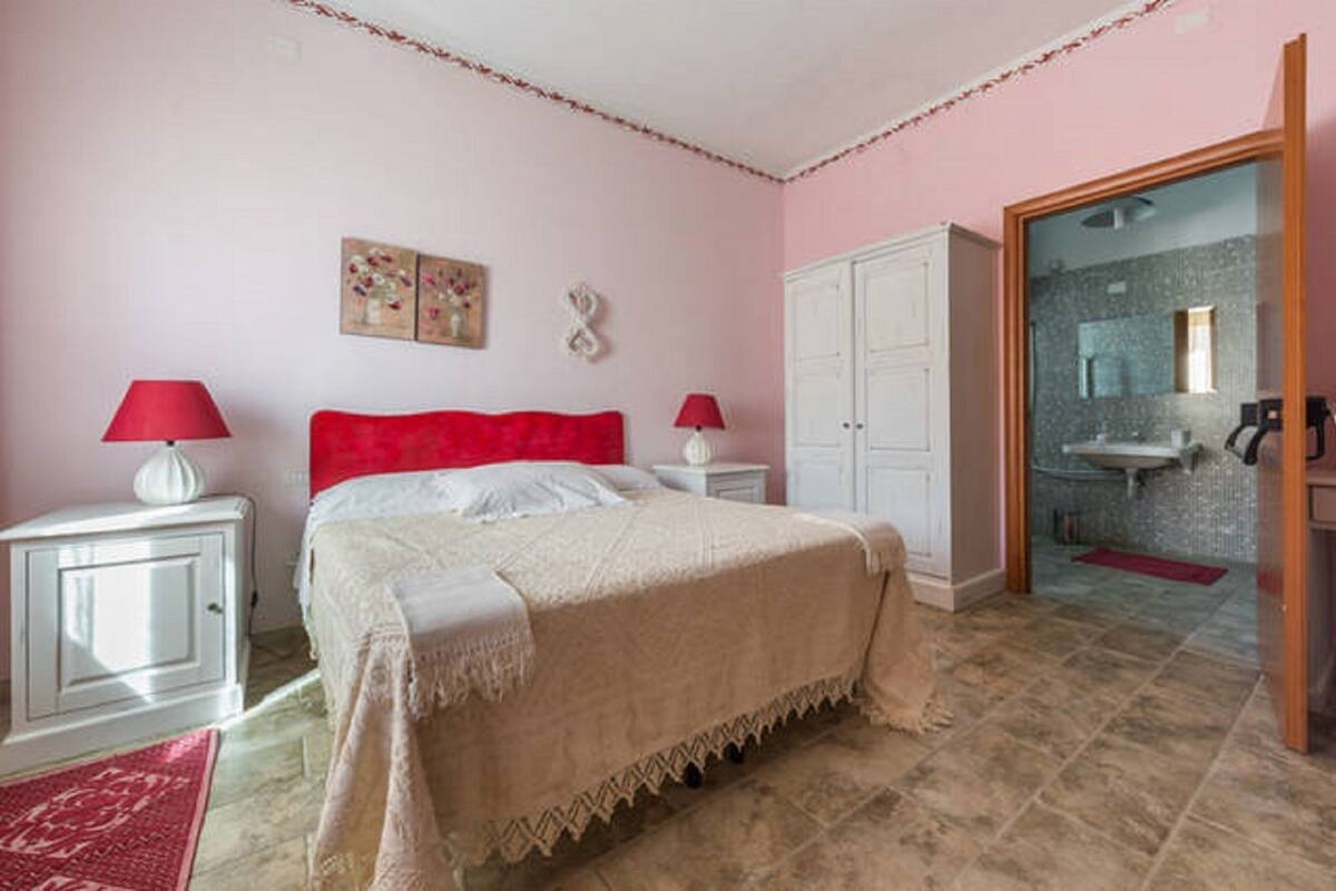 Ein Schlafzimmer mit einem Bett, zwei Nachttischen mit Lampen, einem Kleiderschrank und einem durchgegangenen Badezimmer.