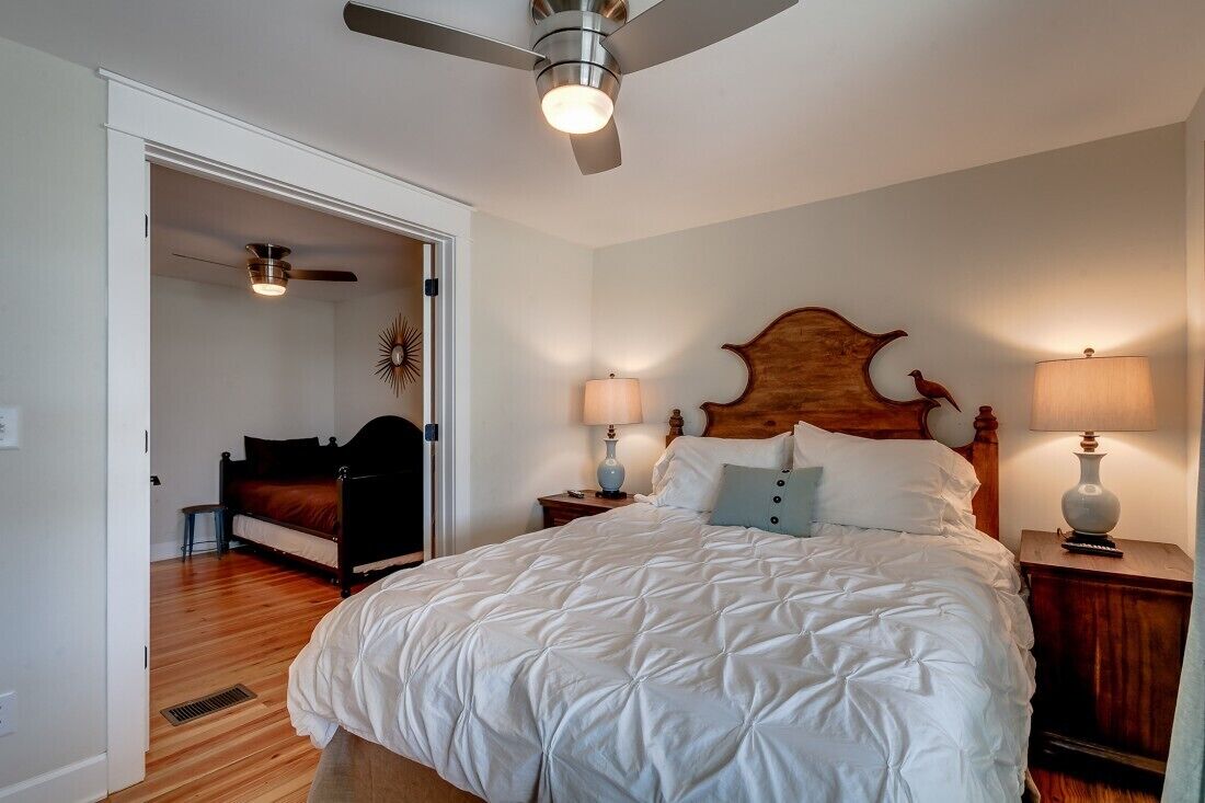 Una camera da letto con un grande letto, due comodini con lampade, una ventola a soffitto e una testiera in legno.