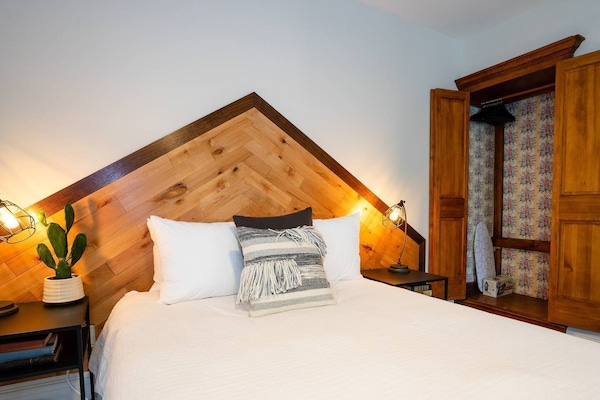 The room includes a wardrobe, as well as an iron + ironing board