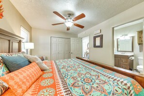Cozy retreat with a large bed, ceiling fan, and dresser with mirror.