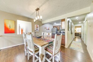 Enjoy meals in this stylish dining area with a wooden table, modern chandelier, and vibrant artwork.