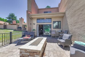 An outdoor patio with a stone fireplace, wicker furniture, and a view of the house interior. - Patio & Mountain View! Ruidoso Golf Condo (Ruidoso)