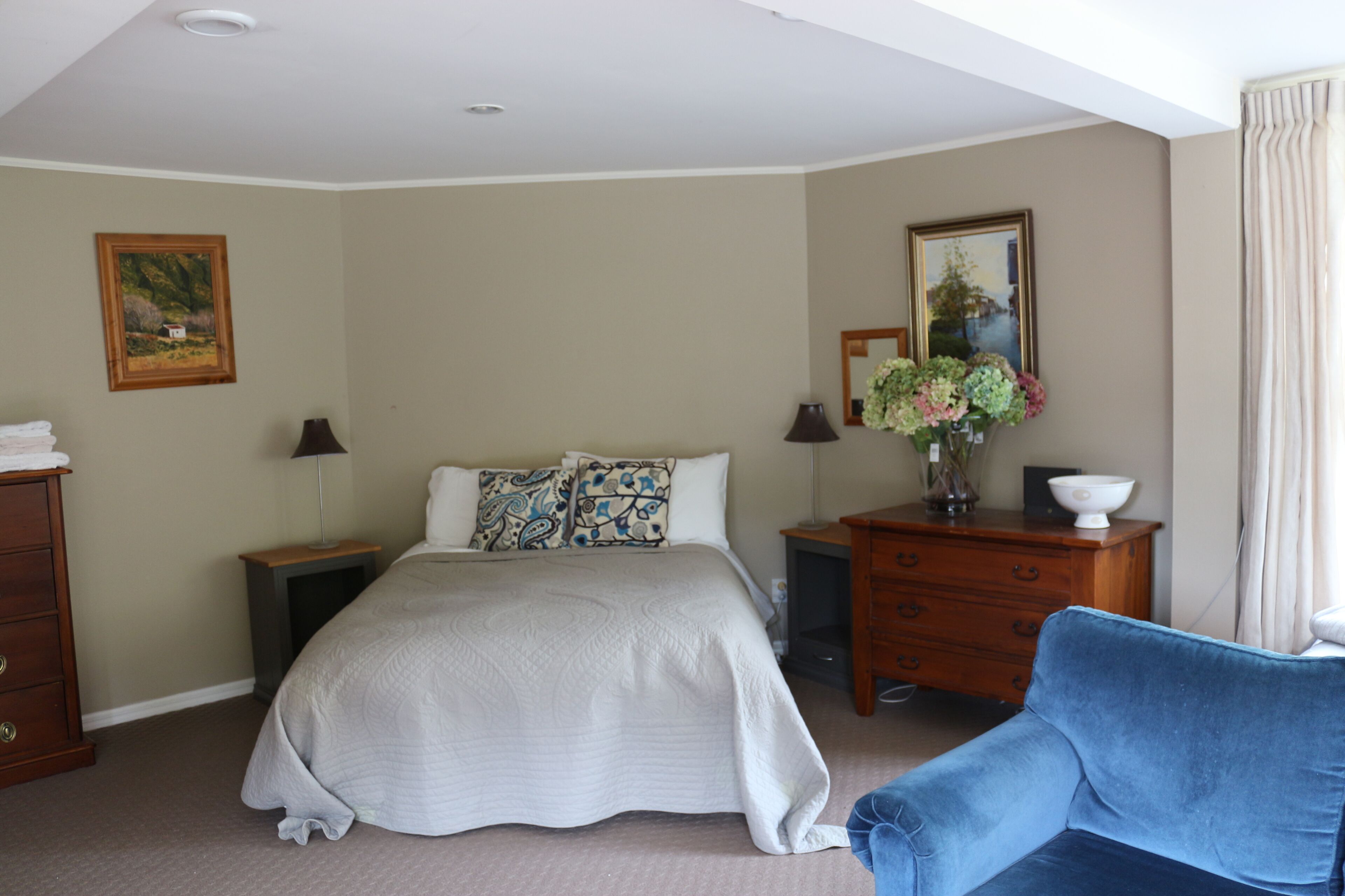 Une chambre à coucher comprenant un lit, une commode, une chaise et une table de chevet.